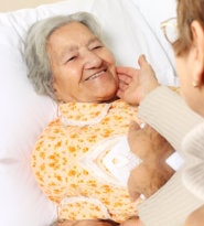 Senior patient in bed with caregiver assisting
